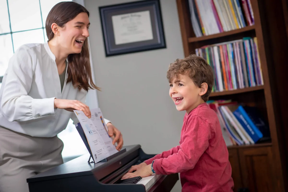 Piano teacher helping a child during a private piano lesson